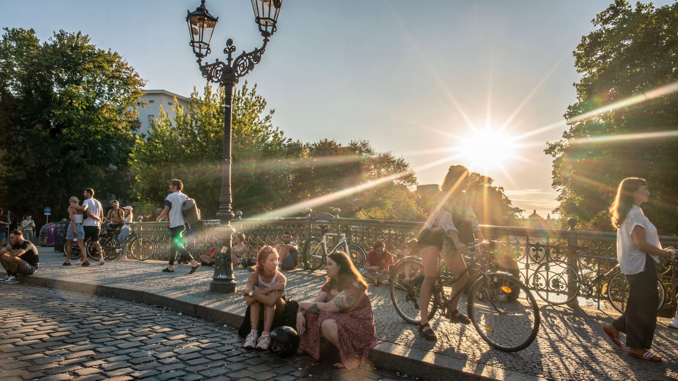 Junge Leute sitzen an der Admiralsbrücke in Kreuzberg (Archivbild): In Berlin wird es sommerlich warm.