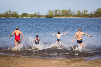 Isernhagen: Eine Familie läuft bei sonnigem Wetter in den Hufeisensee.