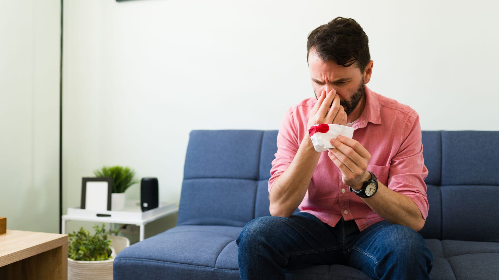 Mann mit Nasenbluten auf dem Sofa