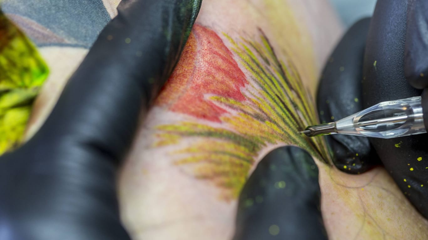 Tätowierer bei der Arbeit mit der Tätowiermaschine (Symbolbild): Das britische Gesundheitsamt warnt vor nicht lizenzierten Tattoostudios.