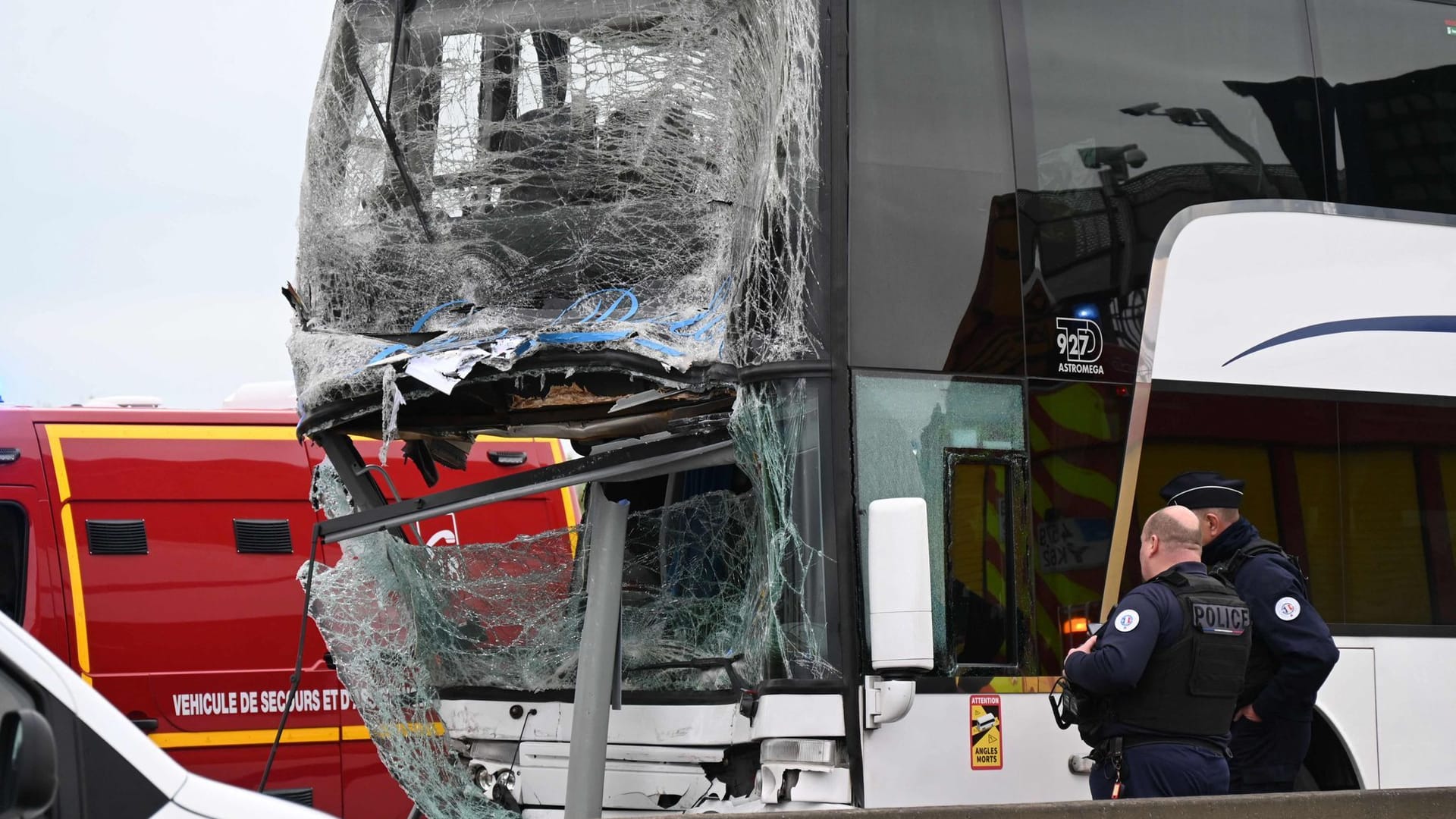 In Calais stehen französische Polizeibeamte neben dem beschädigten Bus.