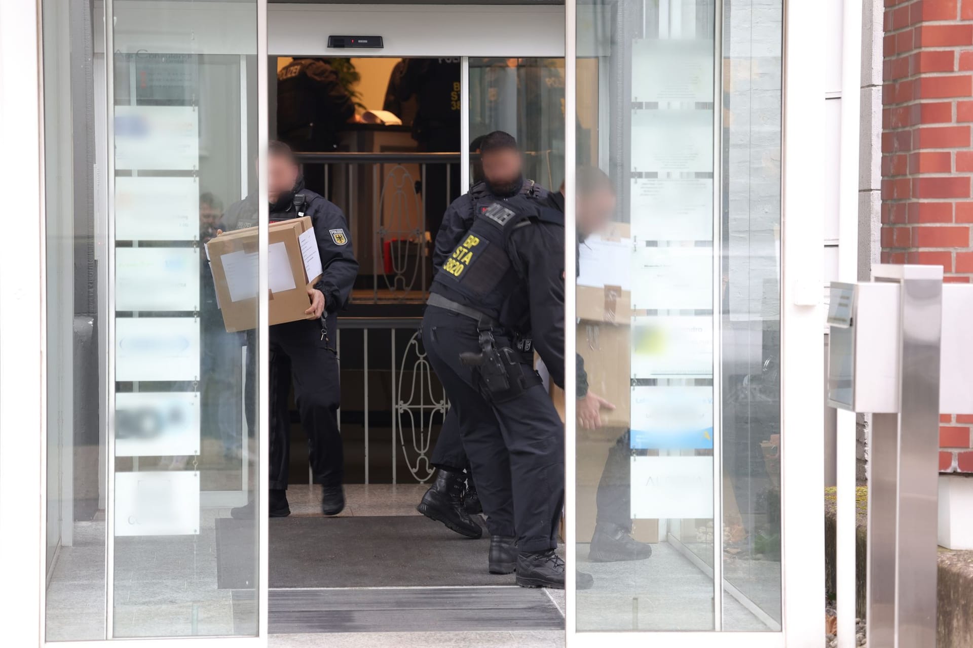 Solingen am 17. April: Polizeibeamte tragen in Kartons sichergestelltes Material aus einem Gebäude.