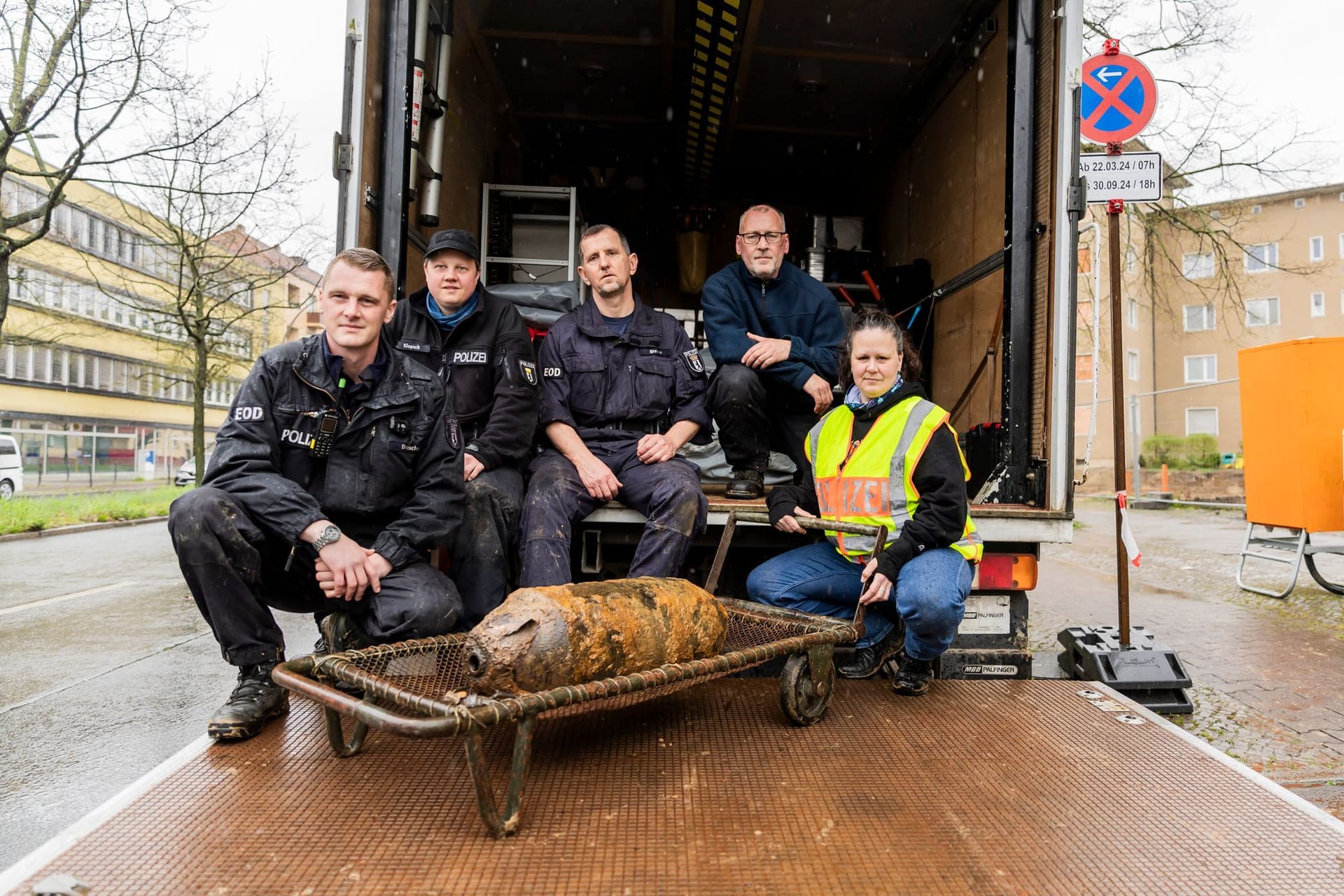 04.04.2024, Berlin: Die Berliner Polizei Feuerwerker Maximilian Drescher (l-r), Patrick Klopsch, Thomas Grabow, Torsten Kienas sowie Claudia Reidenbach, Fachgruppenleiterin des Kampfmittelräumdienster der Berlin Polizei, sitzen nach erfolgreicher Entschärfung hinter einer sowjetischen Weltkriegsbombe vom Typ FAB 100 auf der Ladefläche eines LKWs des Kampfmittelräumdienstes.