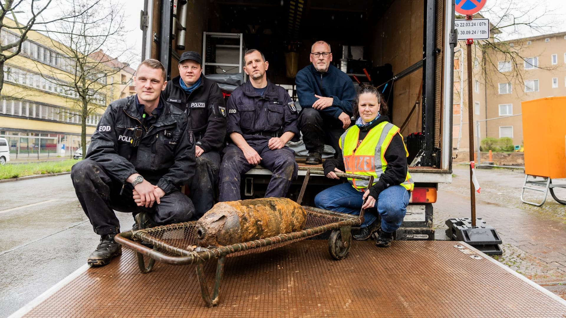 04.04.2024, Berlin: Die Berliner Polizei Feuerwerker Maximilian Drescher (l-r), Patrick Klopsch, Thomas Grabow, Torsten Kienas sowie Claudia Reidenbach, Fachgruppenleiterin des Kampfmittelräumdienster der Berlin Polizei, sitzen nach erfolgreicher Entschärfung hinter einer sowjetischen Weltkriegsbombe vom Typ FAB 100 auf der Ladefläche eines LKWs des Kampfmittelräumdienstes.