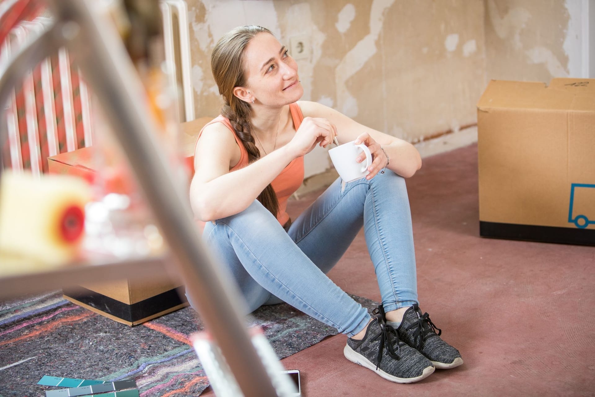 Junge Frau mit Kaffeebecher beim Renovieren