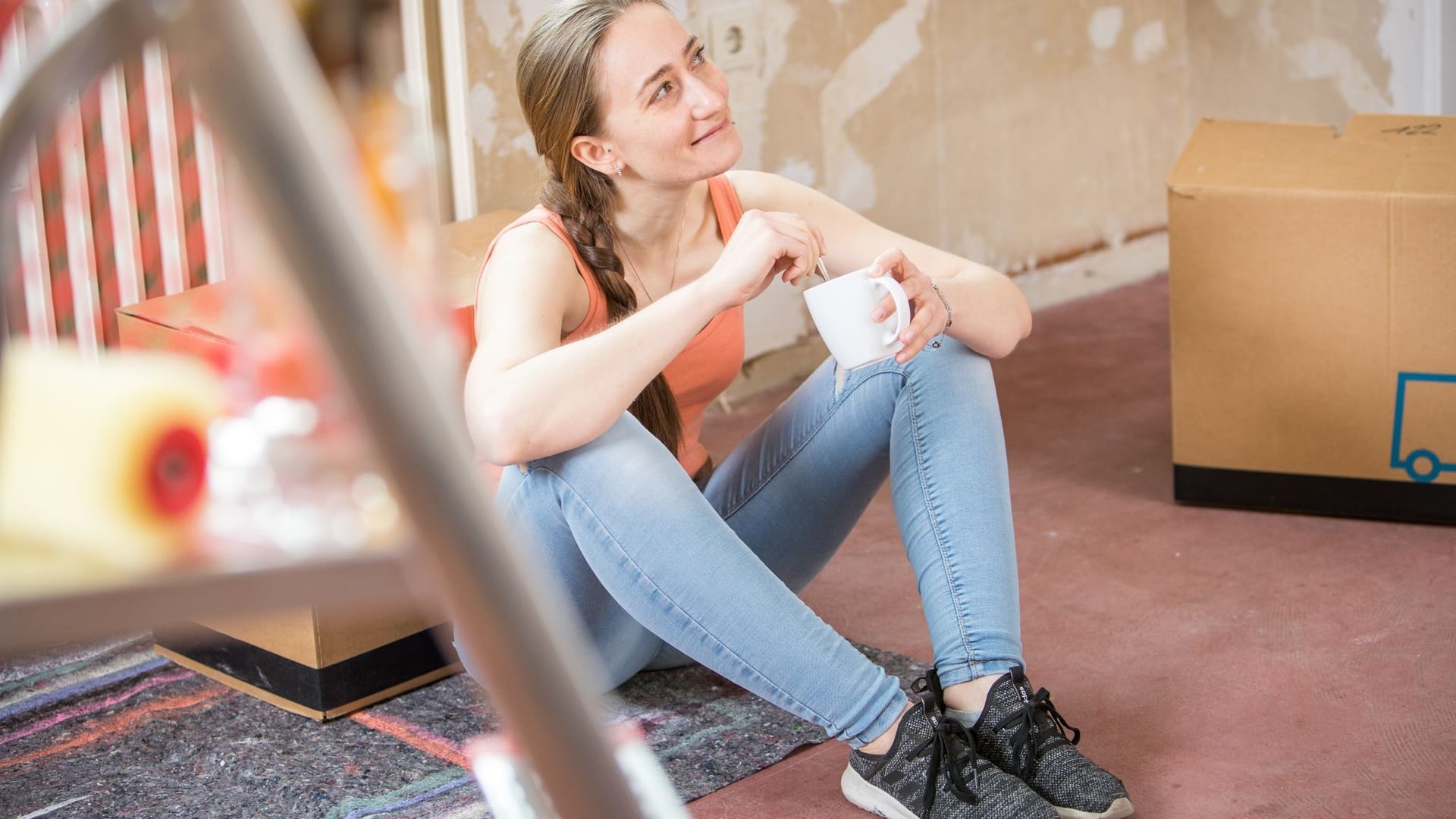 Junge Frau mit Kaffeebecher beim Renovieren