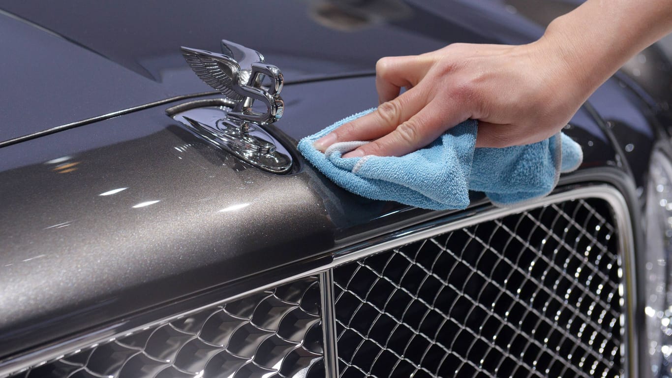 Eine Frau reinigt die Kühlerhaube eines Bentleys: Für viele Menschen bleiben solche Autos ein Traum, andere können sich den Luxus leisten.