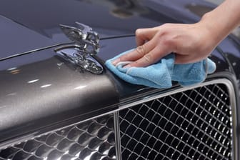 Eine Frau reinigt die Kühlerhaube eines Bentleys: Für viele Menschen bleiben solche Autos ein Traum, andere können sich den Luxus leisten.