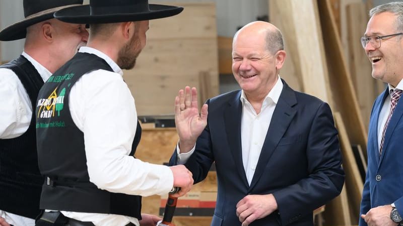 Bundeskanzler Olaf Scholz (SPD, 3.v.l.) scherzt bei seinem Besuch in einem Dresdner Handwerksbetrieb im Holzbau mit den Zimmermeistern Ralf Lepski (l), Felix Lepski (2.v.l.) und Jörg Dittrich (r), dem Präsidenten des Zentralverbandes des Deutschen Handwerks (ZDH) und Präsident der Handwerkskammer Dresden.