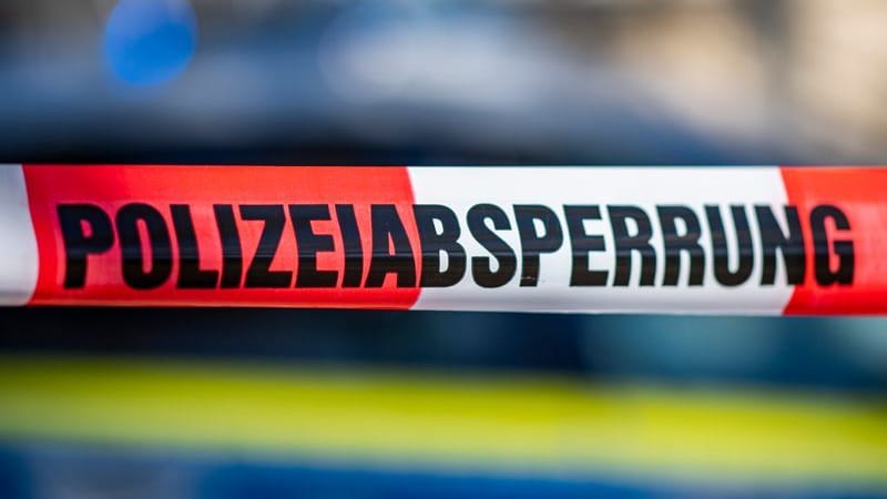 Ein Absperrband mit der Aufschrift «Polizeiabsperrung» ist vor einem Polizeiwagen aufgespannt.