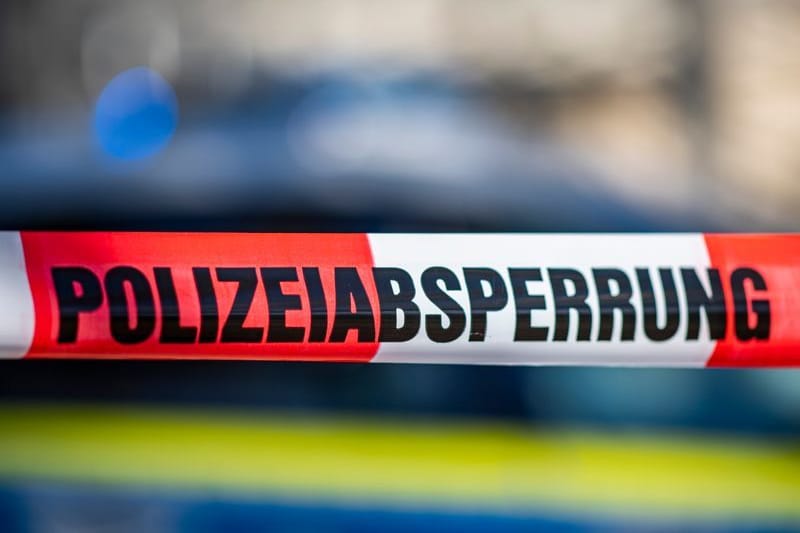 Ein Absperrband mit der Aufschrift «Polizeiabsperrung» ist vor einem Polizeiwagen aufgespannt.