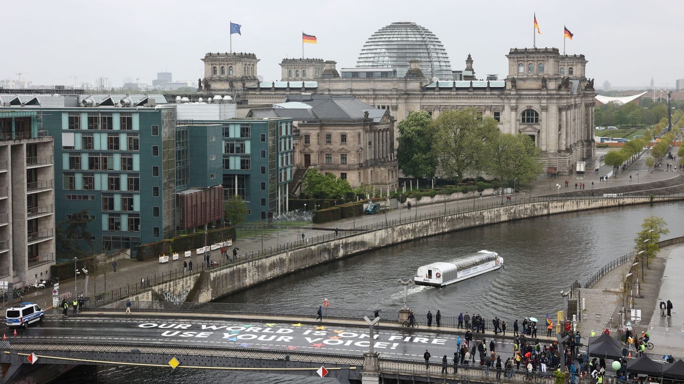 Activists stand next to a message which they painted on a bridge during the global Fridays for Future climate strike in Berlin, Germany, April 19, 2024