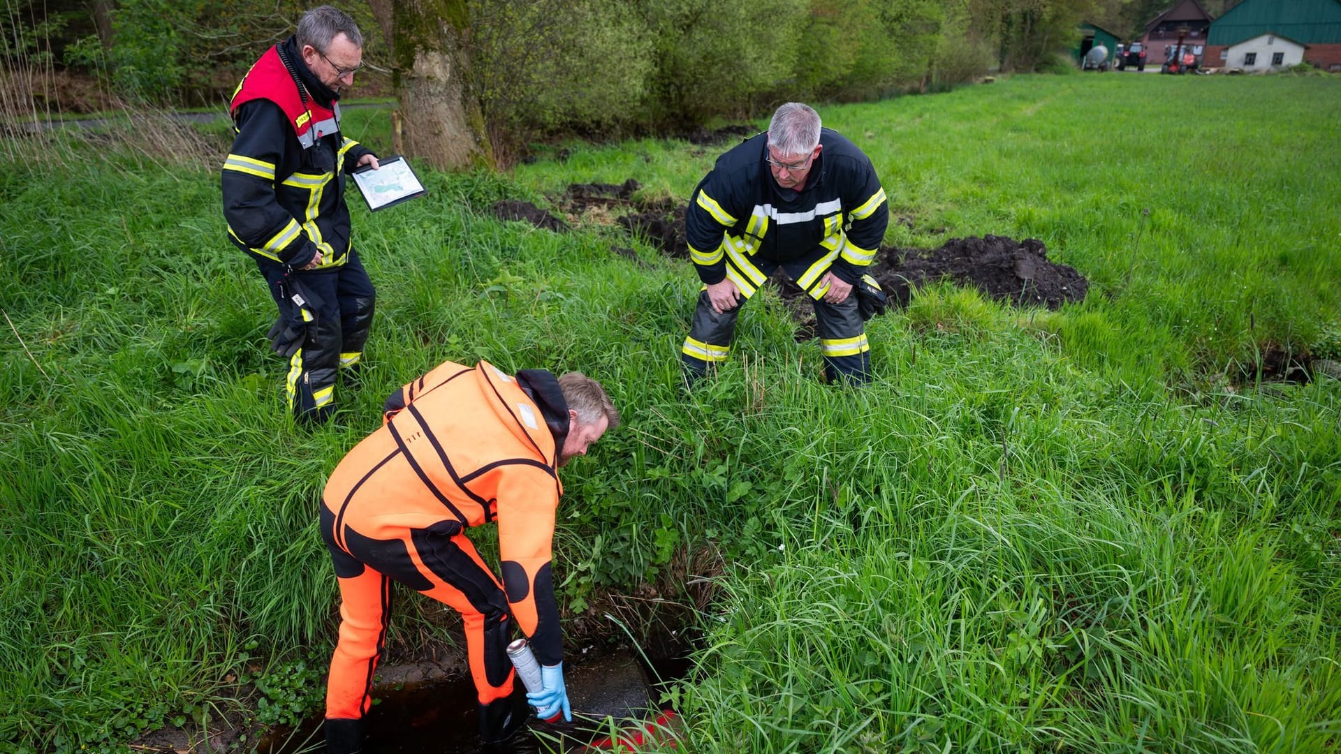 Ehrenamtliche Helfer der Feuerwehr durchsuchen Gräben und Rohre.