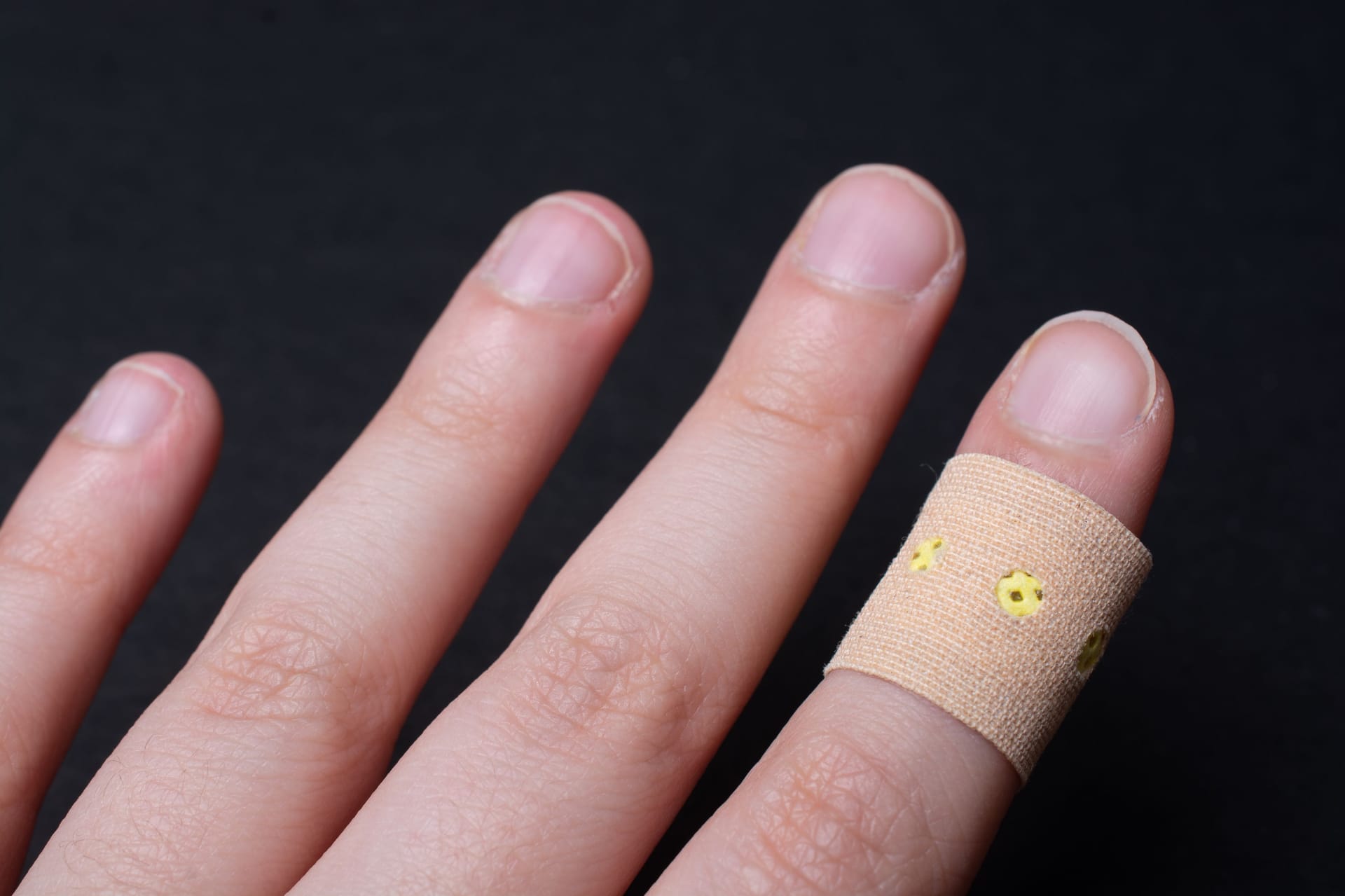 Bandage patch on a person's finger on a black background