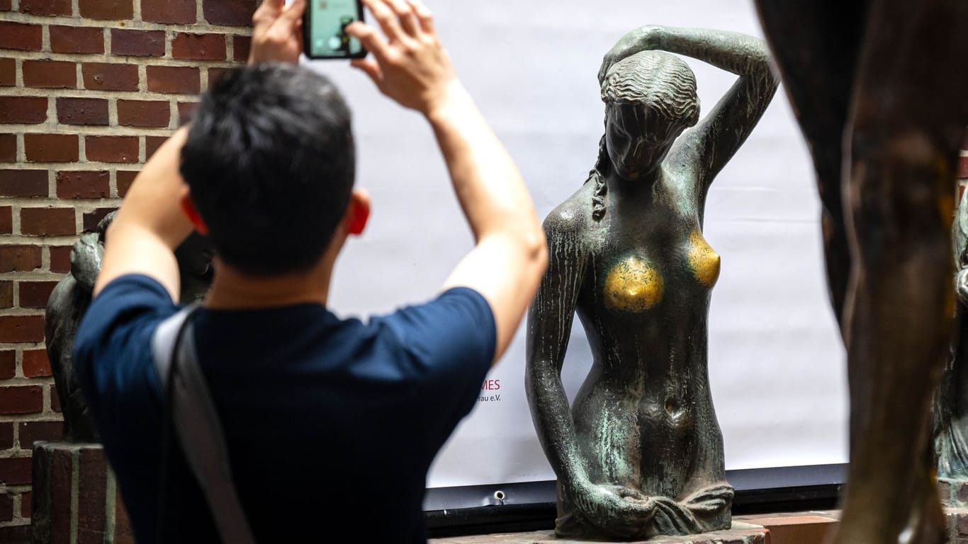 Eine Person fotografiert den QR-Code eines Plakats: Davor steht die Bronzeskulptur "Jugend" des Künstlers Bernhard Hoetger.