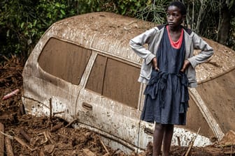 Ein kenianisches Mädchen steht neben einem im Schlamm versunkenen Auto. Aufgrund der starken Regenfälle sind schon über 140 Menschen in Kenia verstorben.