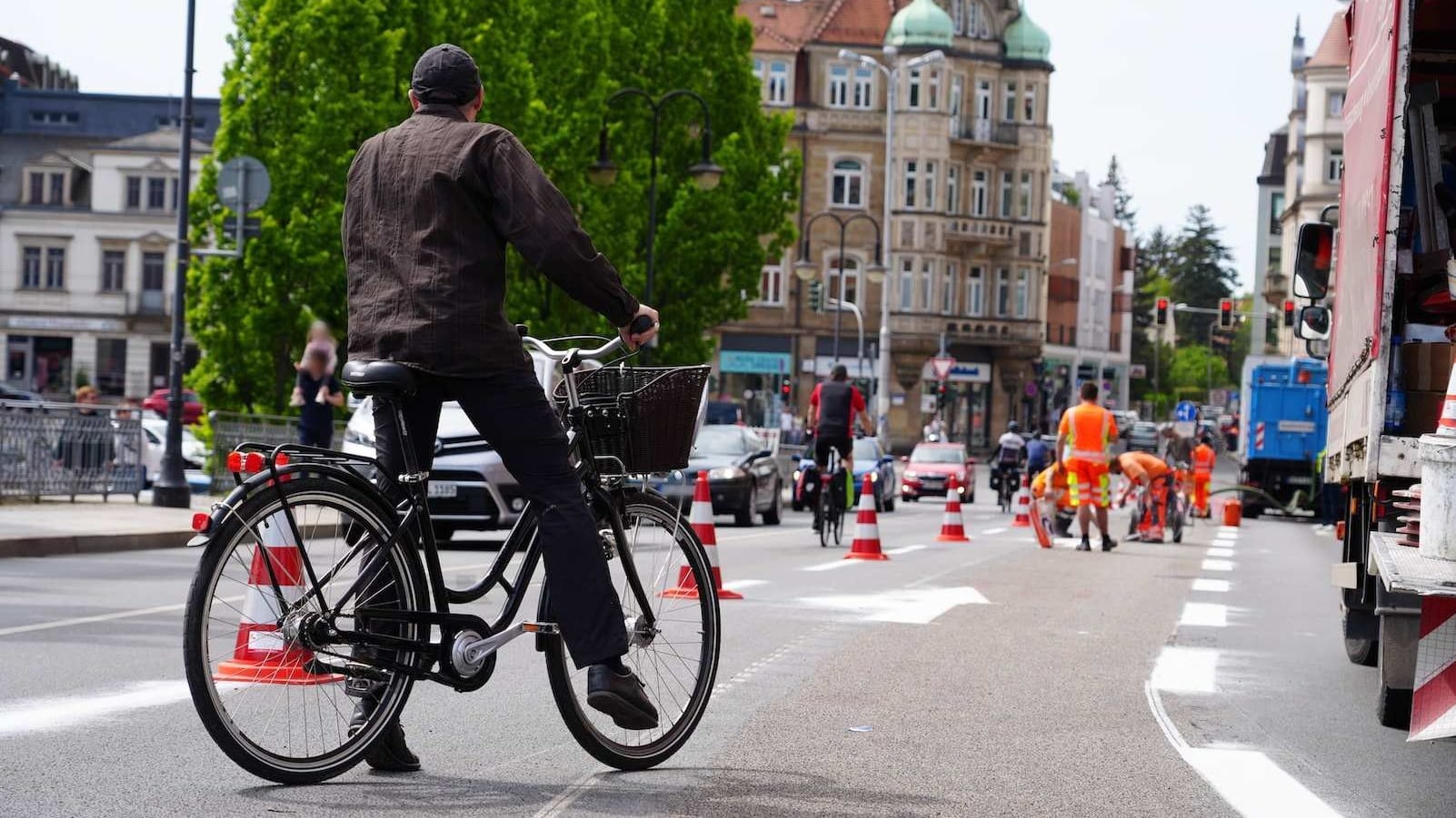 Ein Radfahrer beobachtet die Rückbauarbeiten: Die Markierungen des Verkehrsversuchs am Blauen Wunder werden entfernt.