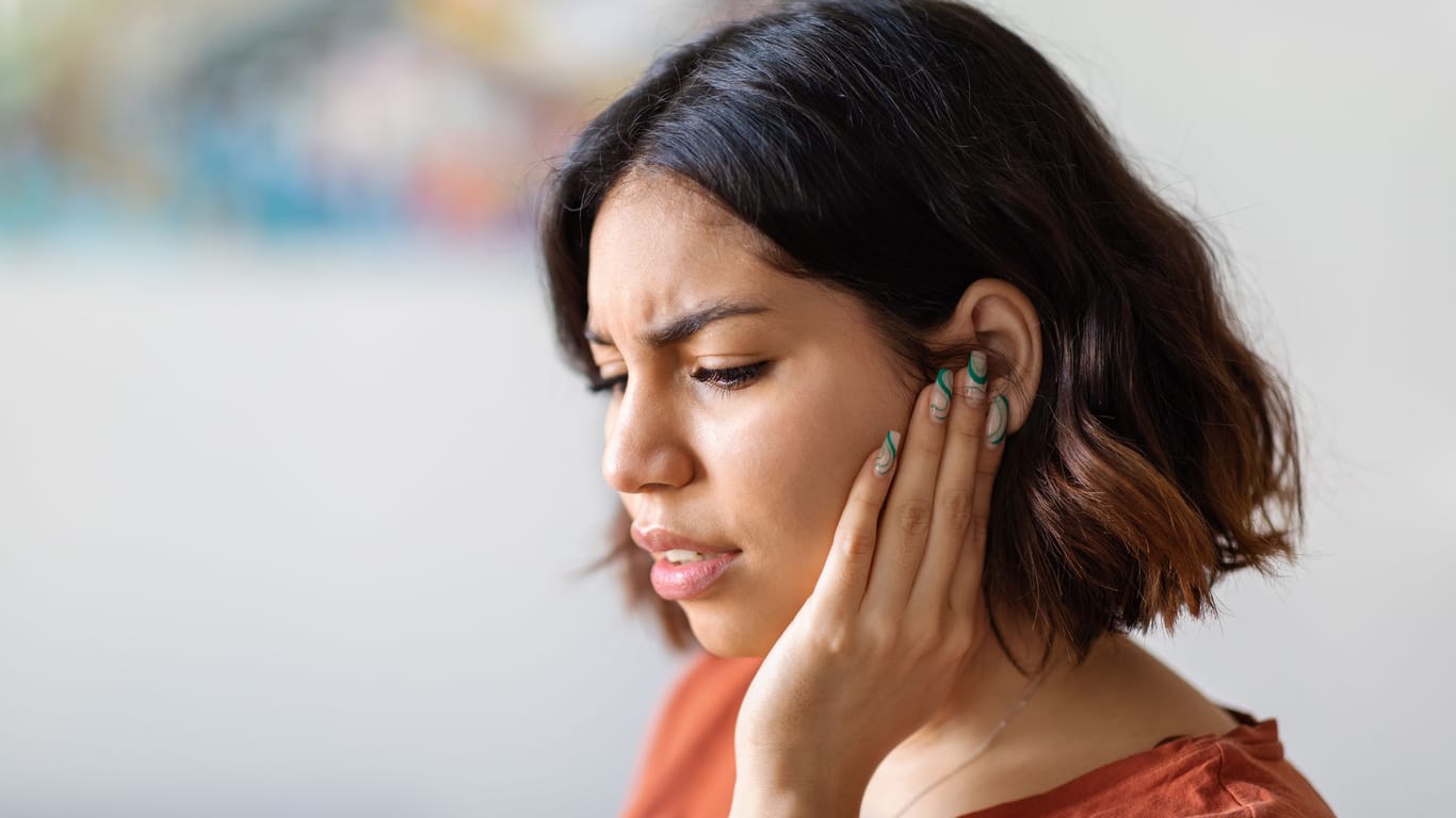 Frau mit Ohrenschmerzen: Bei einer Gehörgangsentzündung sind Hausmittel häufig Teil der Behandlung.