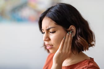 Frau mit Ohrenschmerzen: Bei einer Gehörgangsentzündung sind Hausmittel häufig Teil der Behandlung.