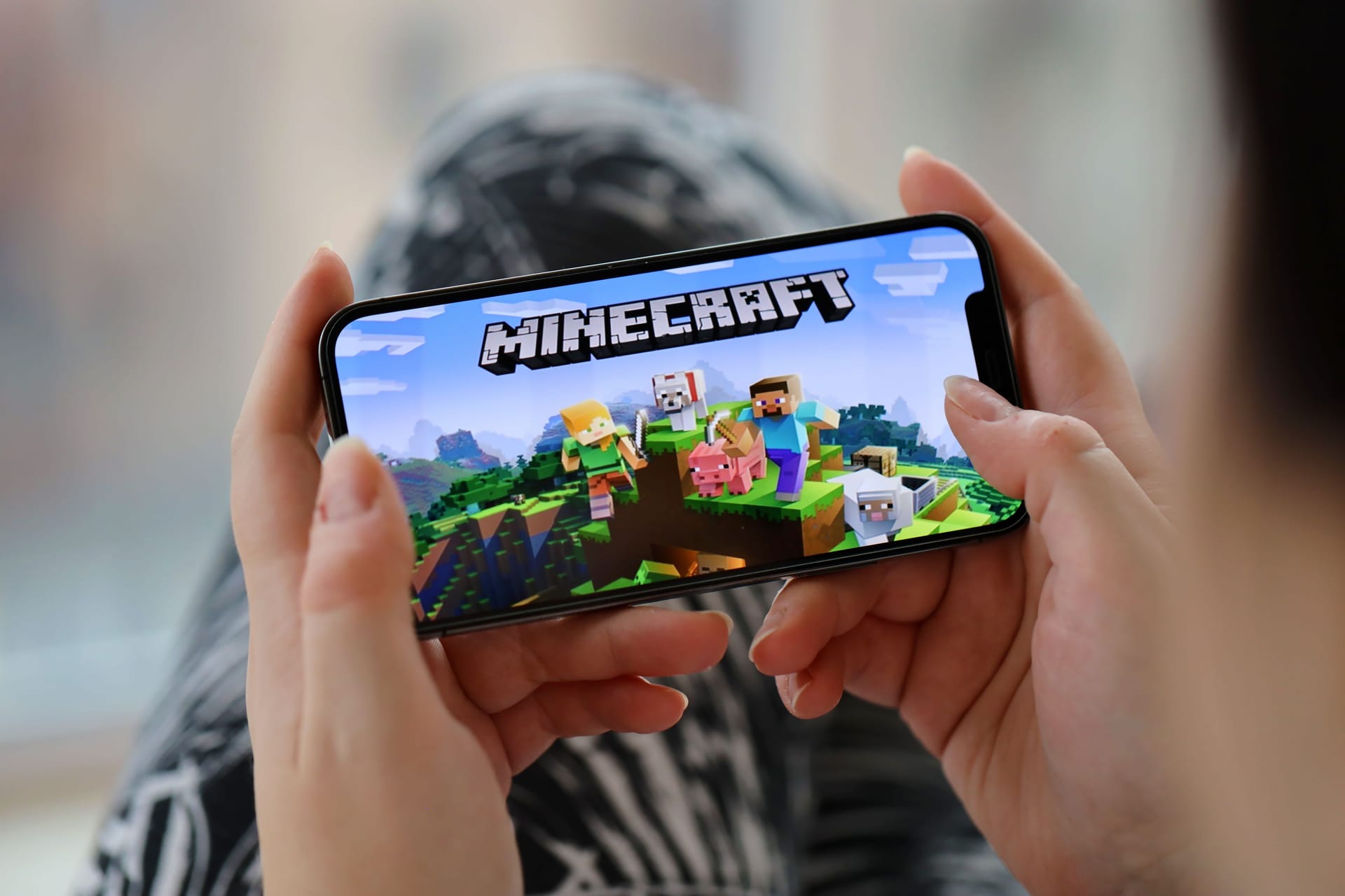 Minecraft mobile iOS game on iPhone 15 smartphone screen in female hands during mobile gameplay