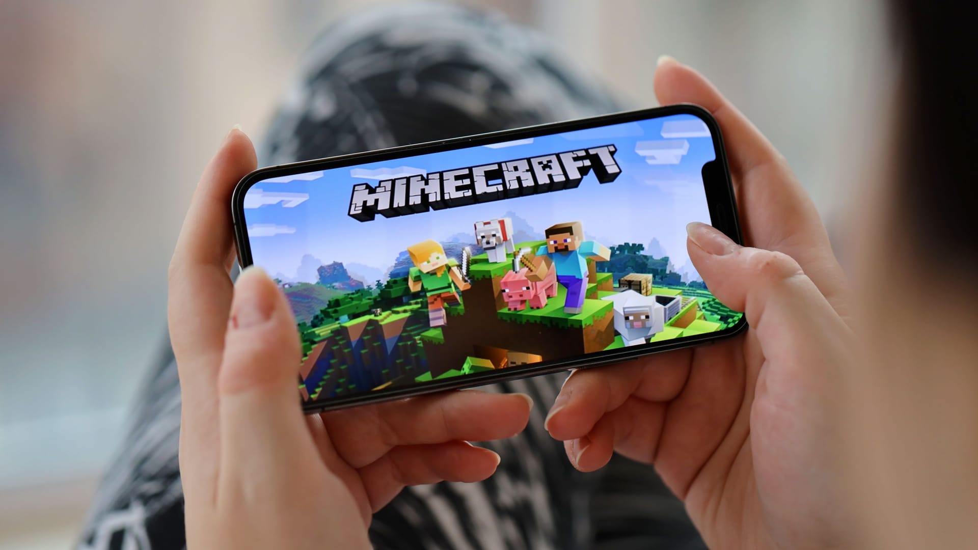 Minecraft mobile iOS game on iPhone 15 smartphone screen in female hands during mobile gameplay