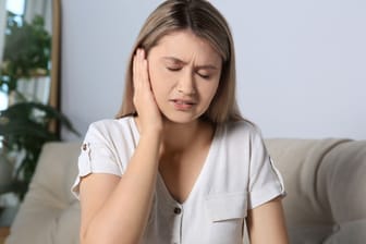 Junge Frau mit Ohrenschmerzen: Manchmal dauert es länger, bis eine Gehörgangsentzündung weggeht.