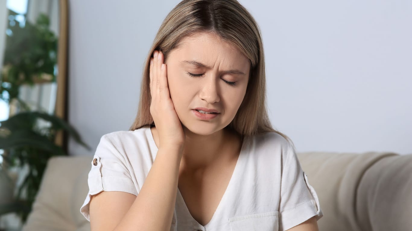 Junge Frau mit Ohrenschmerzen: Manchmal dauert es länger, bis eine Gehörgangsentzündung weggeht.