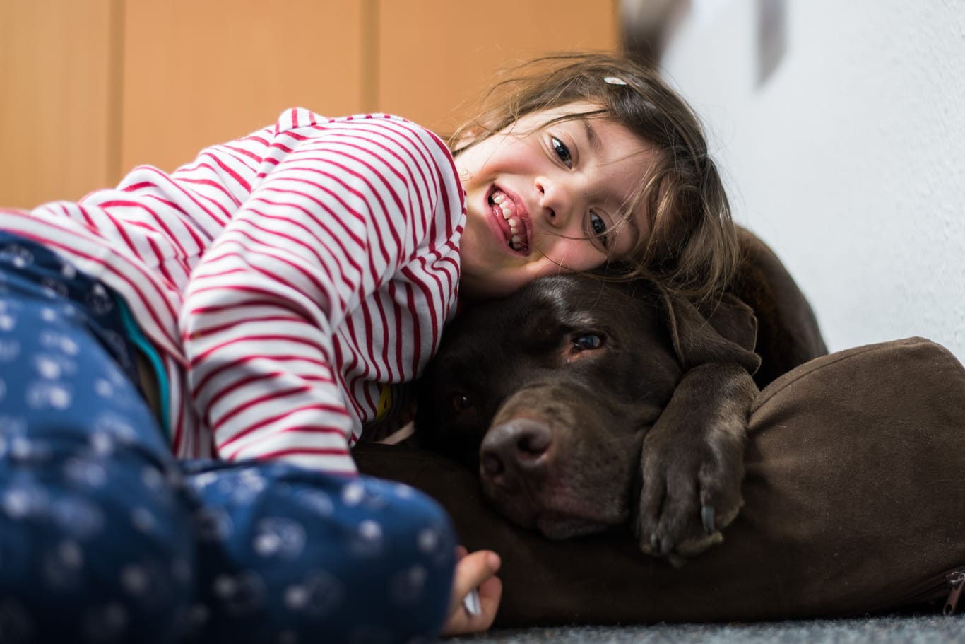 Ein kleines Mädchen kuschelt mit einem Hund (Symbolbild): Nora hat große Tierliebe bewiesen.
