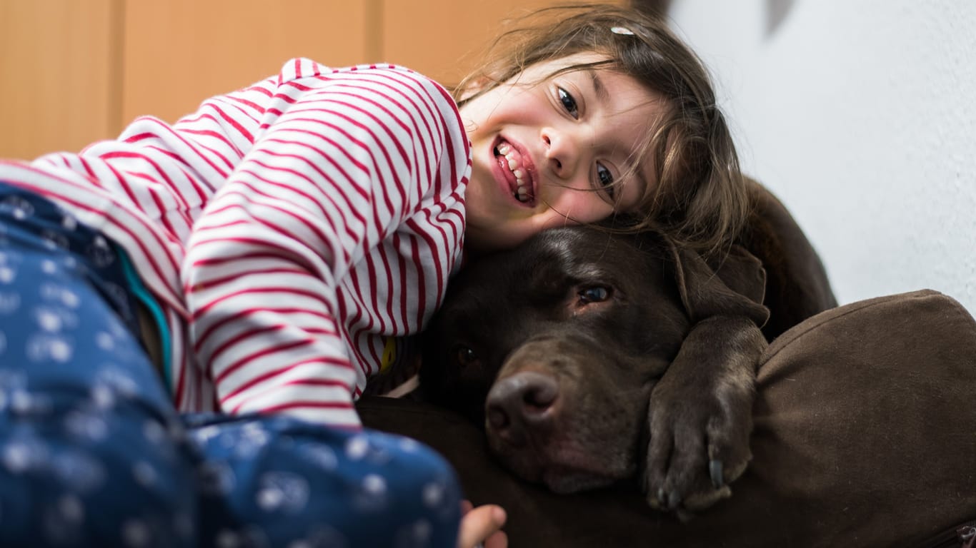 Ein kleines Mädchen kuschelt mit einem Hund (Symbolbild): Nora hat große Tierliebe bewiesen.