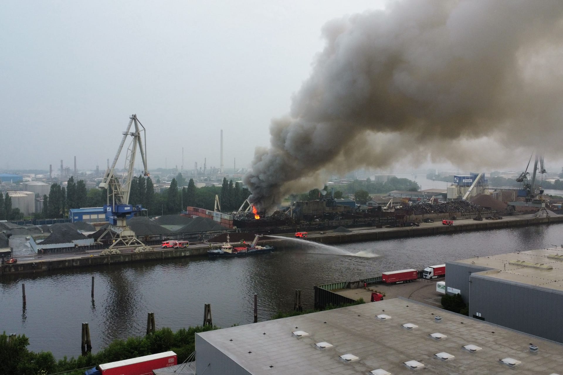 Dichter Rauch steigt über dem Hamburger Hafen auf: Die Löscharbeiten laufen mit zahlreichen Einsatzkräften.