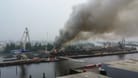 Dichter Rauch steigt über dem Hamburger Hafen auf: Die Löscharbeiten laufen mit zahlreichen Einsatzkräften.