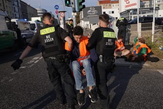 Polizisten führen einen Klimaaktivisten ab (Archivbild): Ein Polizist wies in Berlin einen Klimaaktivisten zurecht, der sich hinter ein Polizeiauto gelegt hat.