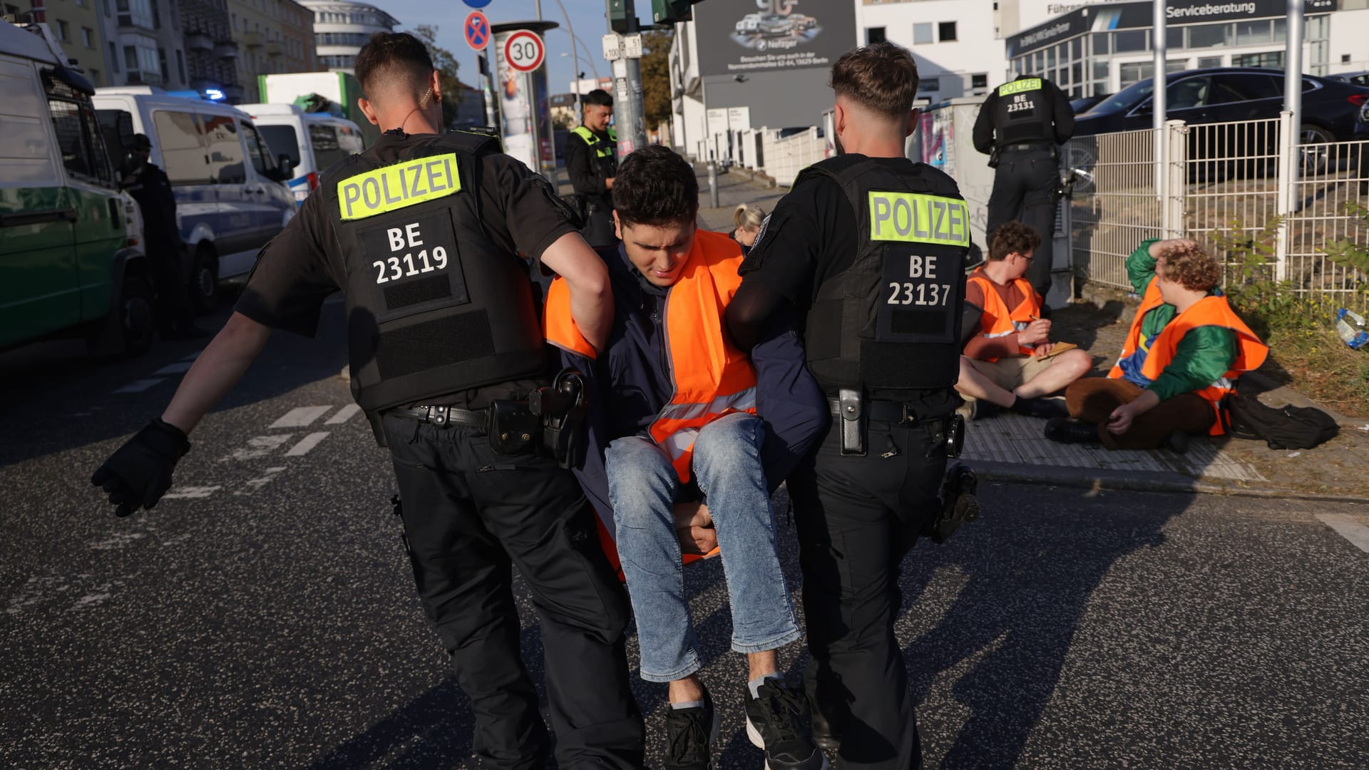 Polizisten führen einen Klimaaktivisten ab (Archivbild): Ein Polizist wies in Berlin einen Klimaaktivisten zurecht, der sich hinter ein Polizeiauto gelegt hat.