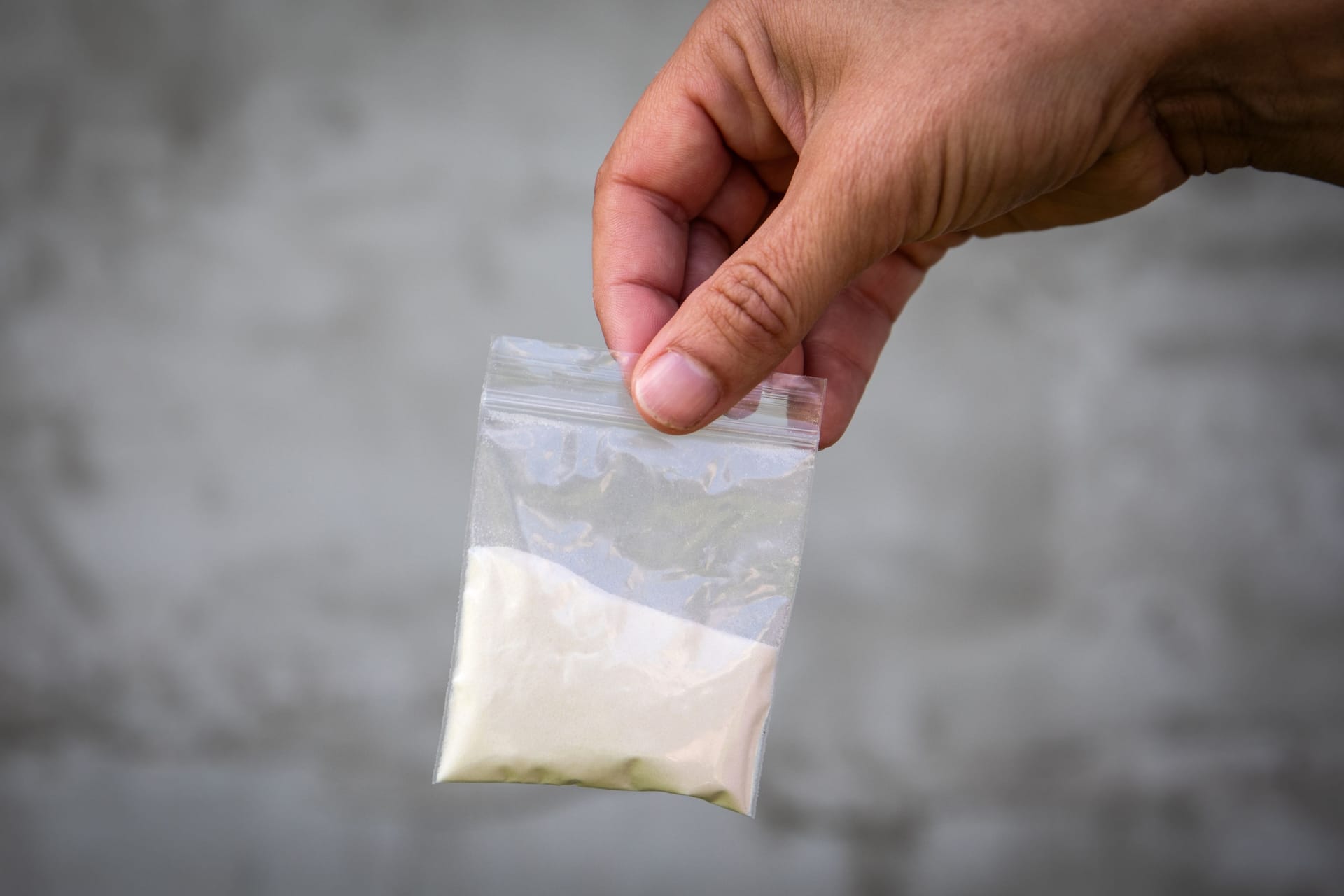 A bag of white powder in hand. Image for prohibited substances, addiction concept