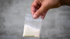 A bag of white powder in hand. Image for prohibited substances, addiction concept