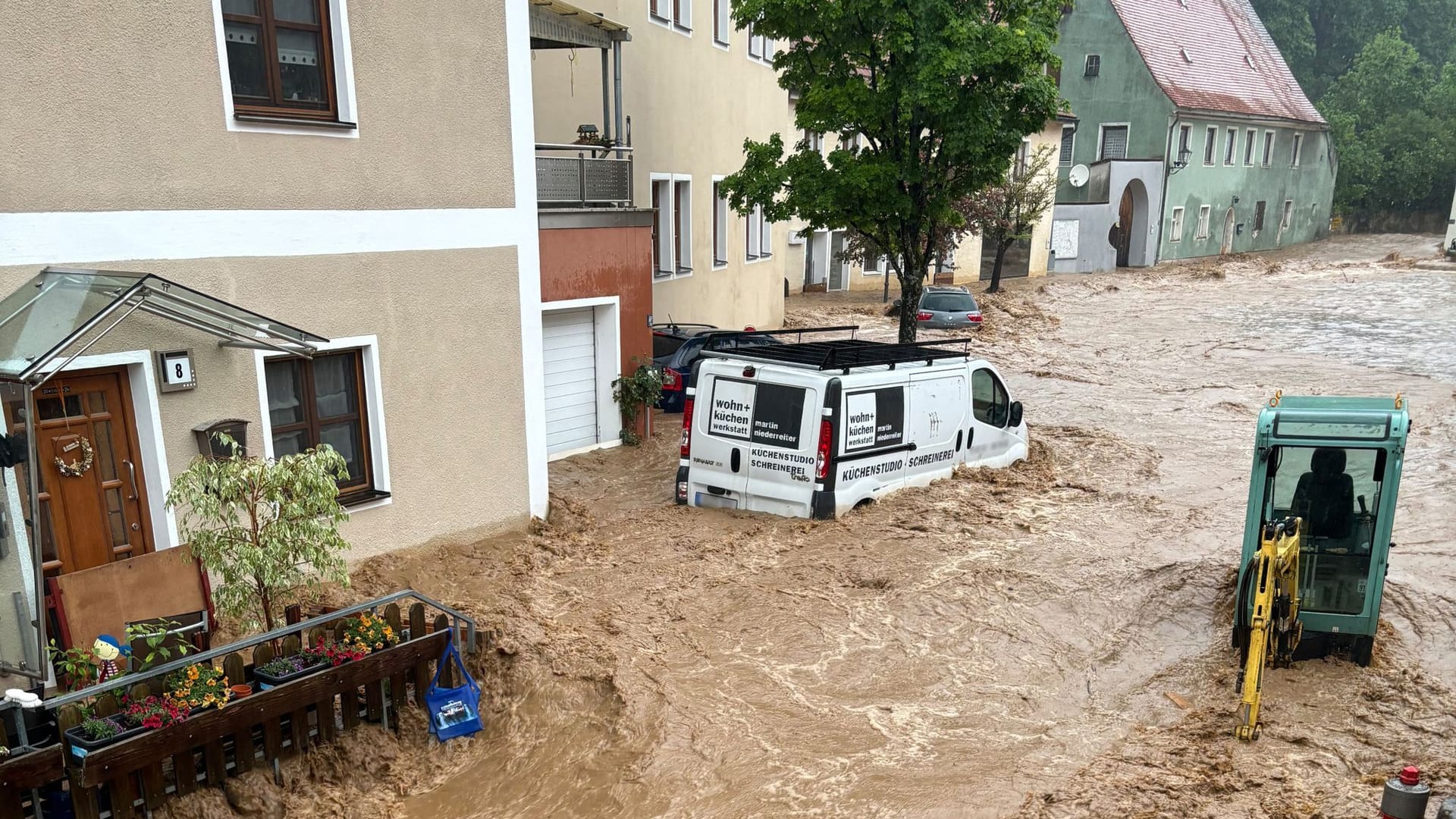 Ein Auto treibt nach starkem Regen in einer Straße im Wasser im bayerischen Kastl.