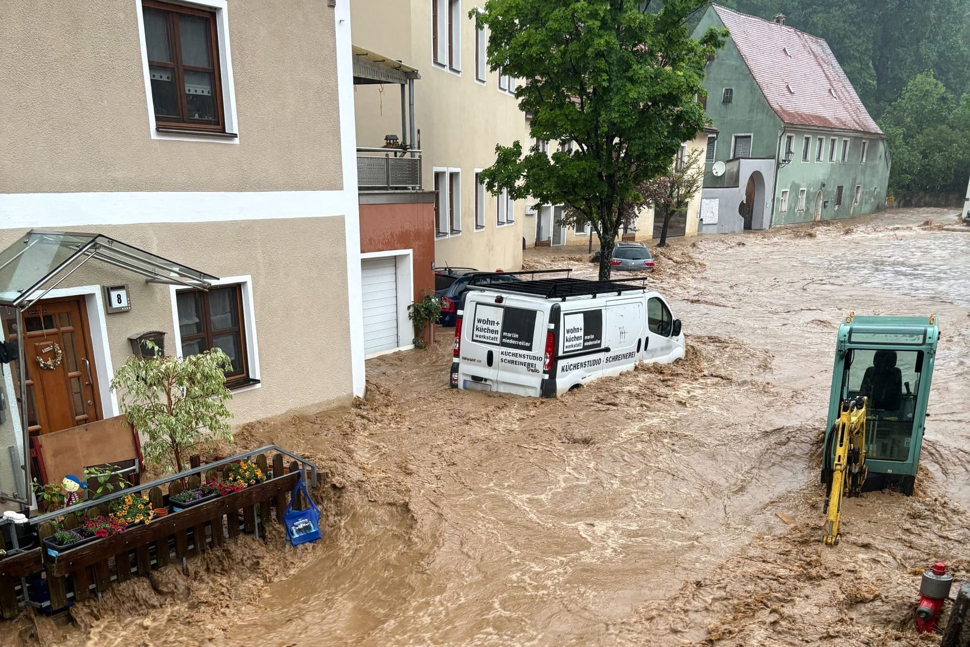 Ein Auto treibt nach starkem Regen in einer Straße im Wasser im bayerischen Kastl.