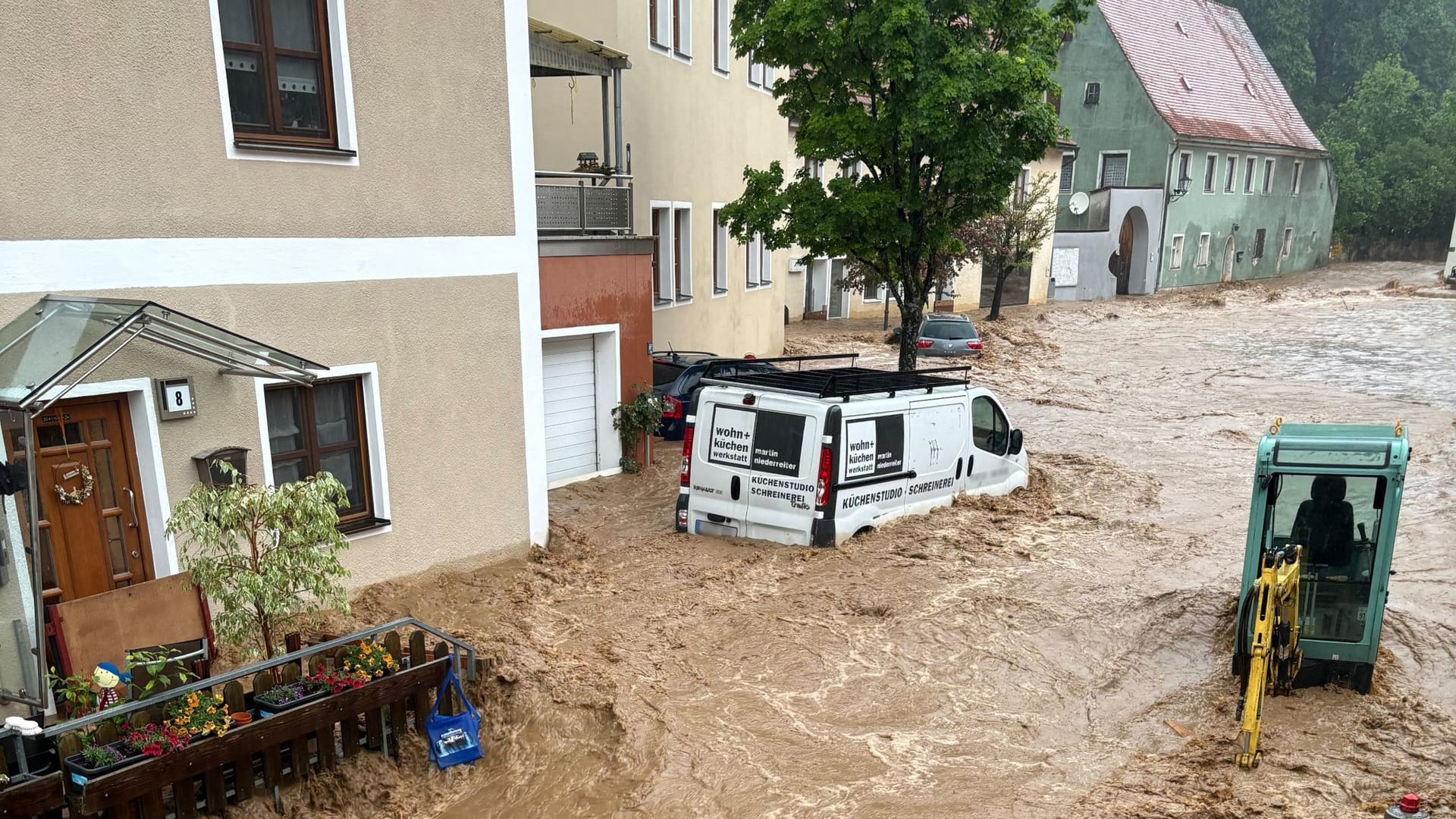 Ein Auto treibt nach starkem Regen in einer Straße im Wasser im bayerischen Kastl.