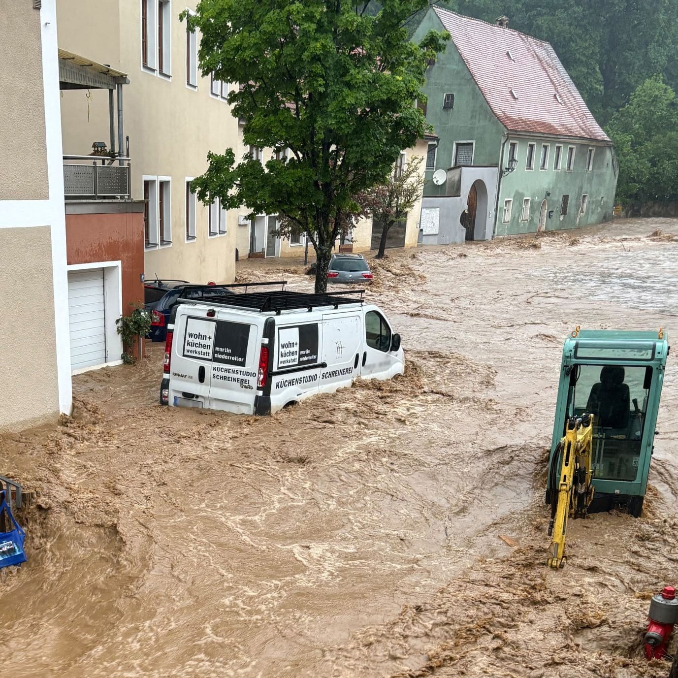 Ein Auto treibt nach starkem Regen in einer Straße im Wasser im bayerischen Kastl.