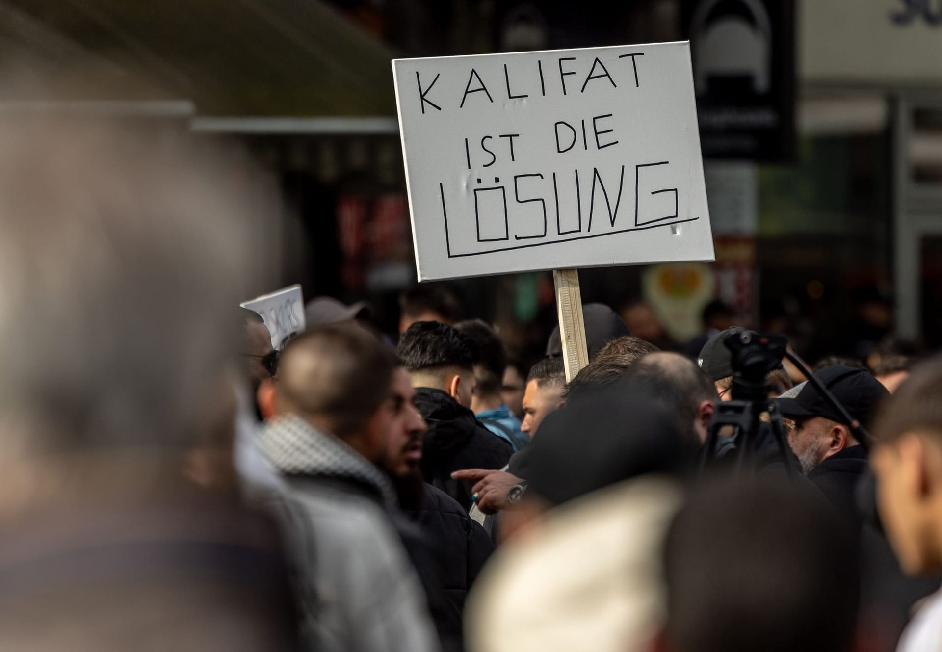 27. April, Hamburg: Teilnehmer einer Islamisten-Demo halten ein Plakat mit der Aufschrift "Kalifat ist die Lösung" in die Höhe.