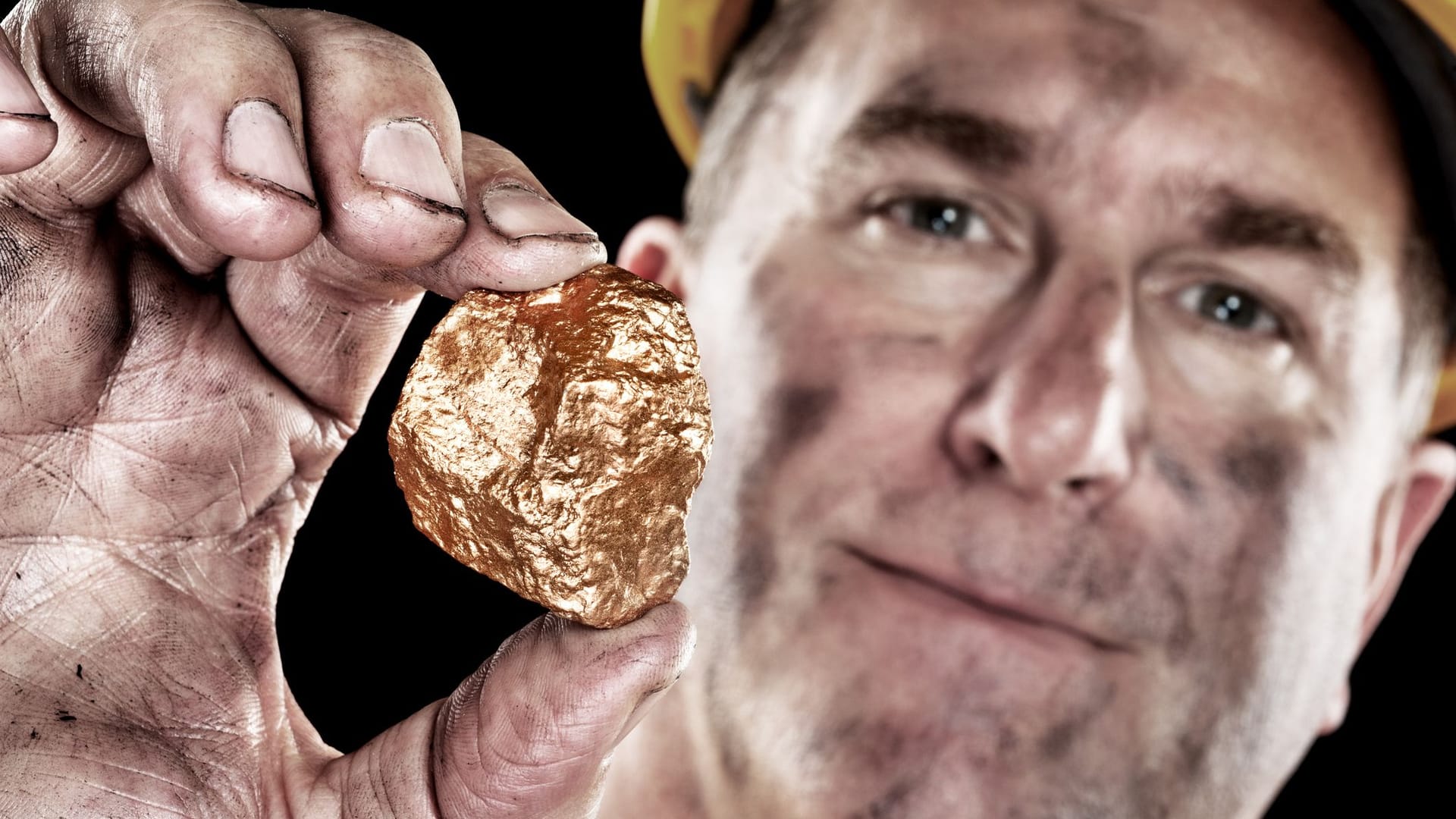 Goldschürfer hält ein Gold-Nugget in die Kamera