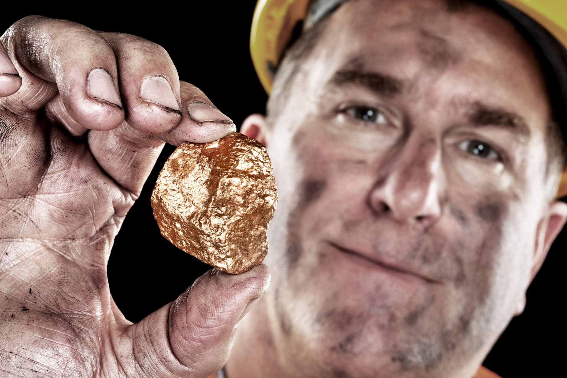 Goldschürfer hält ein Gold-Nugget in die Kamera