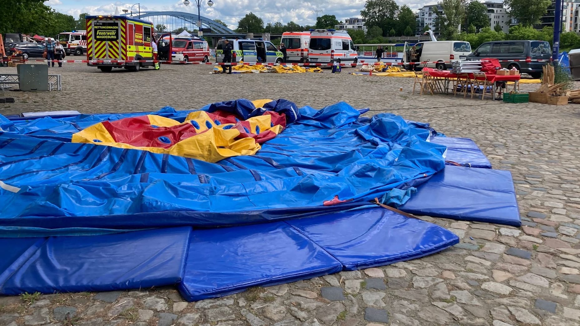 Einsatzfahrzeuge stehen am Elbufer hinter einer zusammengefallenen Hüpfburg: Mehrere Kinder sind am Sonntag in Magdeburg verletzt worden.