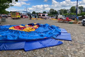 Einsatzfahrzeuge stehen am Elbufer hinter einer zusammengefallenen Hüpfburg: Mehrere Kinder sind am Sonntag in Magdeburg verletzt worden.