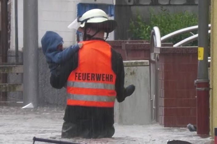 Ein Bild zeigt den 17-Jährigen mit dem Kind in den Fluten.