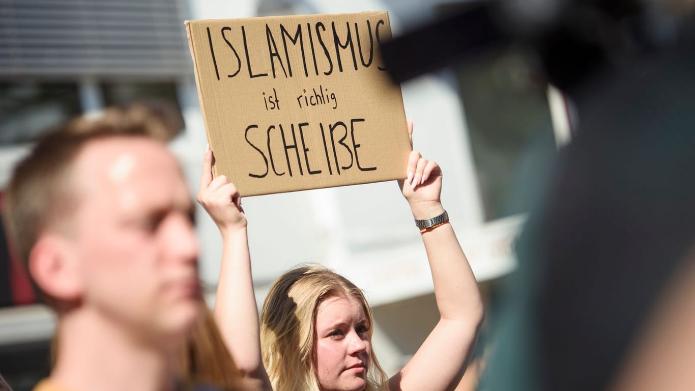 Eine Demonstrantin hält auf einer Gegenkundgebung zu einer Veranstaltung des islamistischen Netzwerks "Muslim Interaktiv" ein Schild in die Höhe.
