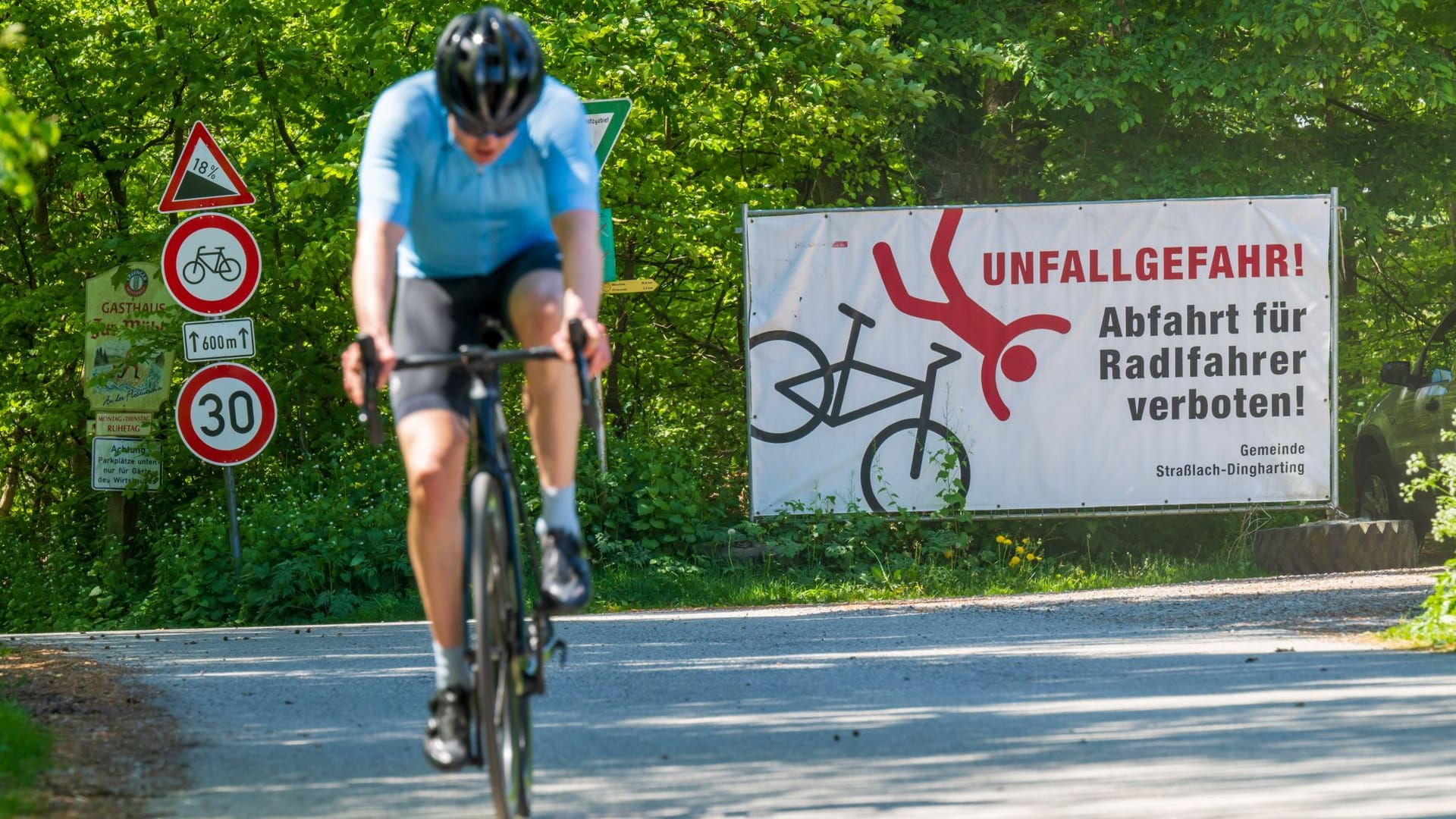 Ein Radfahrer fährt bei Straßlach-Dingharting an einem Schild mit der Aufschrift "Unfallgefahr – Abfahrt für Radfahrer verboten!" vorbei.