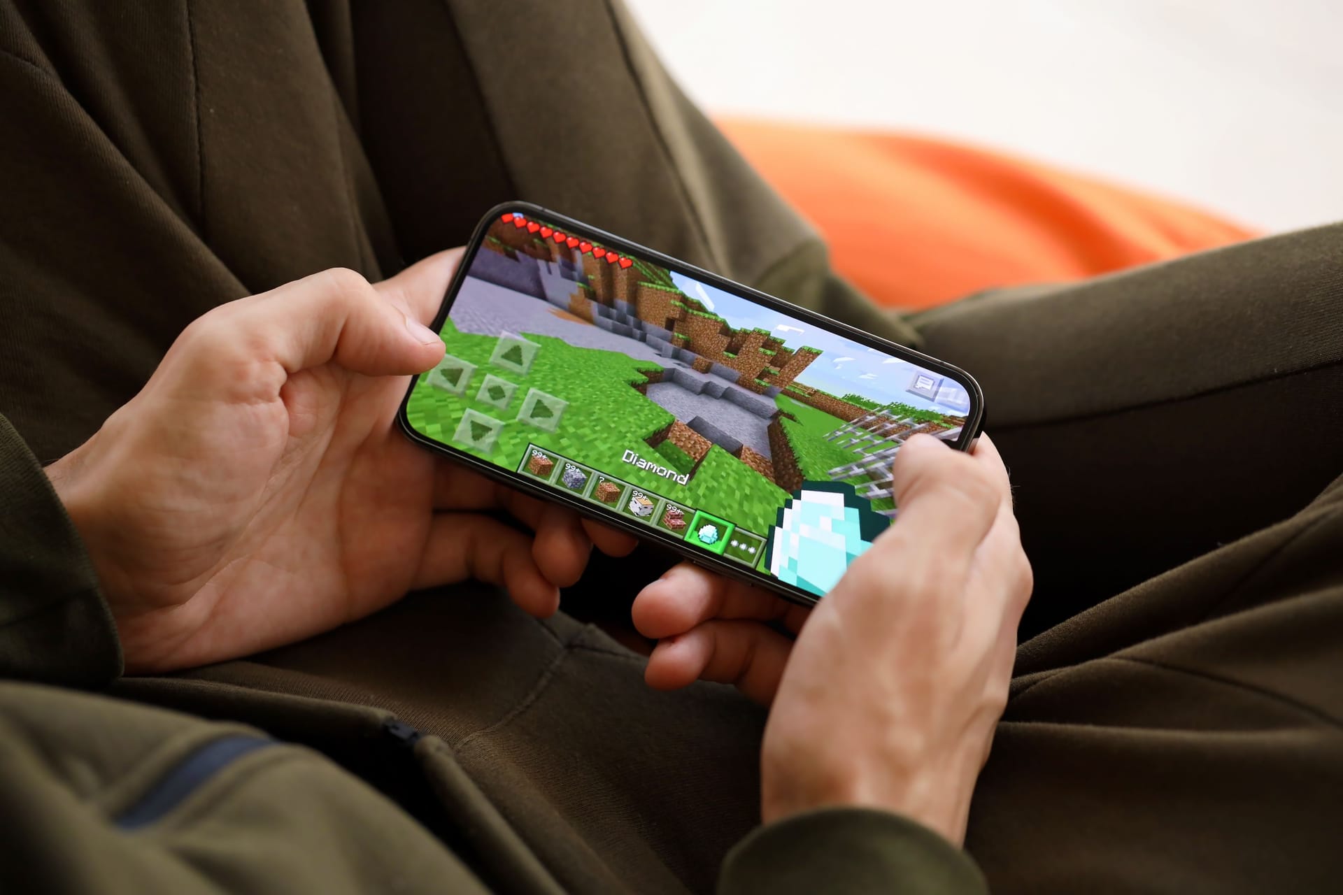 Minecraft mobile iOS game on iPhone 15 smartphone screen in male hands during mobile gameplay