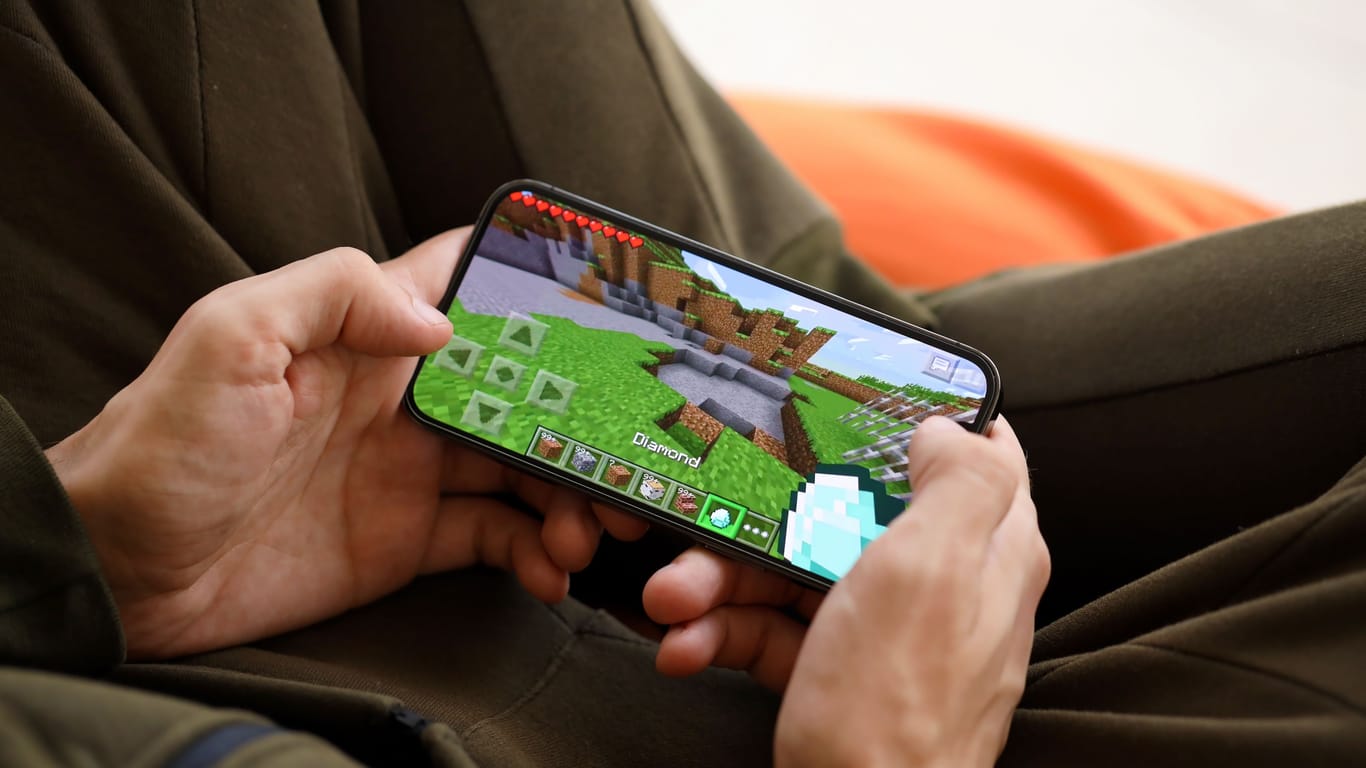 Minecraft mobile iOS game on iPhone 15 smartphone screen in male hands during mobile gameplay