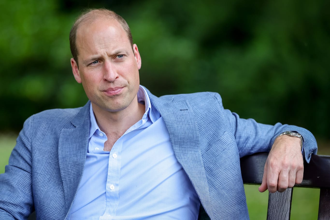 Prinz William sitzt in einem Garten.